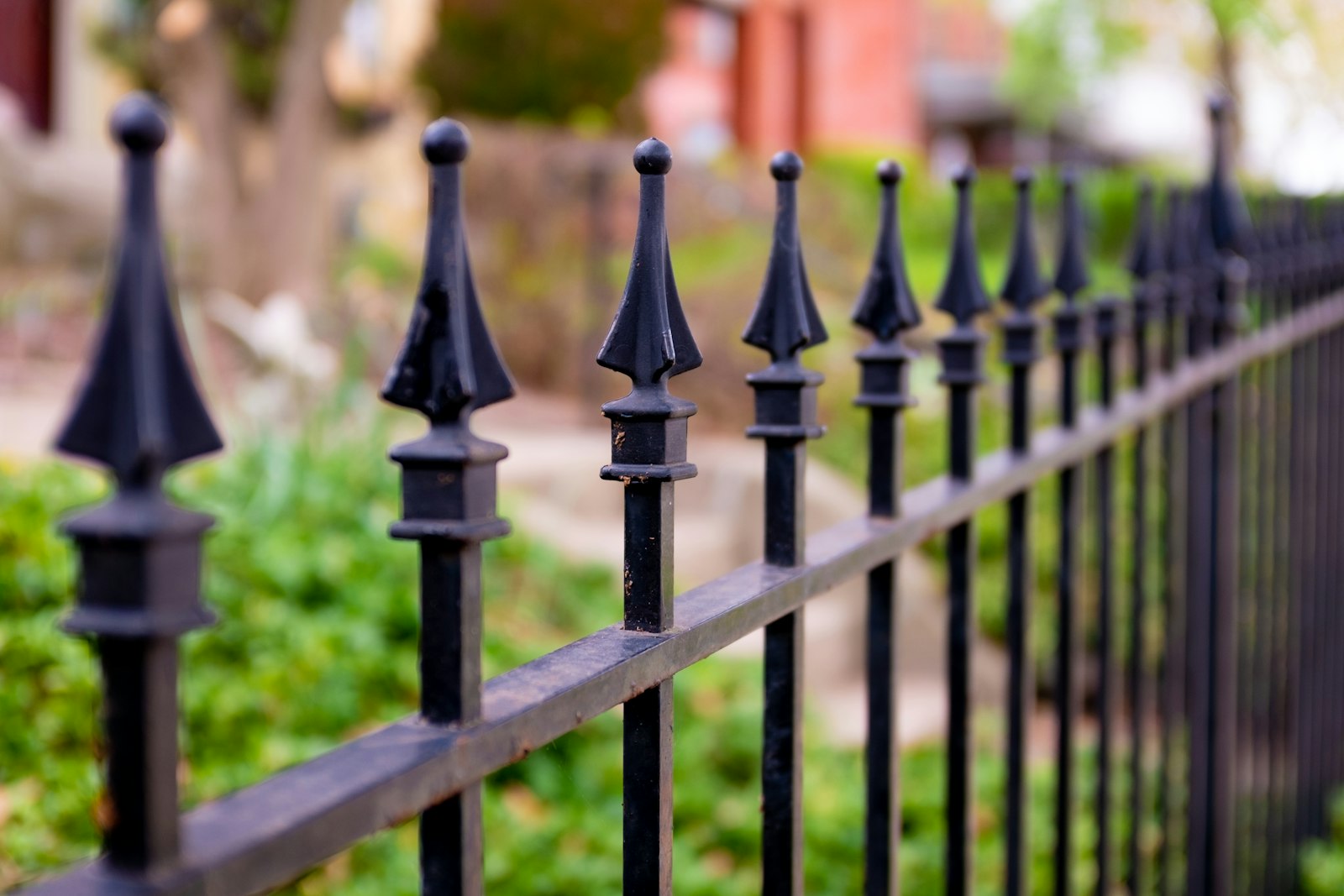 Clôture en fer forgé avec pointes décoratives en bordure de jardin